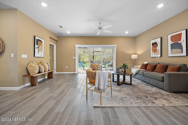 living room with hardwood / wood-style floors, ceiling fan, and a textured ceiling