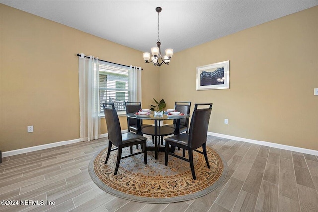 dining space featuring an inviting chandelier, a textured ceiling, and light hardwood / wood-style flooring