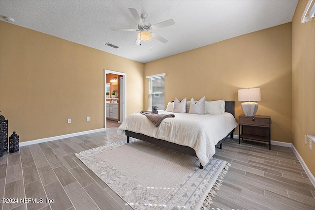 bedroom with hardwood / wood-style floors, ceiling fan, a textured ceiling, and ensuite bath