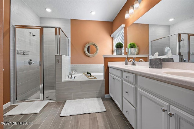 bathroom with vanity, shower with separate bathtub, and a textured ceiling