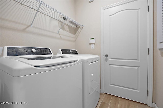 laundry area with washer and clothes dryer and light hardwood / wood-style floors