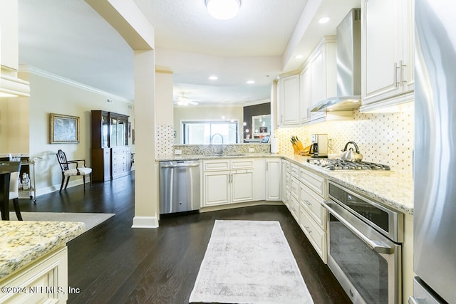 kitchen with appliances with stainless steel finishes, dark hardwood / wood-style flooring, light stone counters, white cabinetry, and crown molding