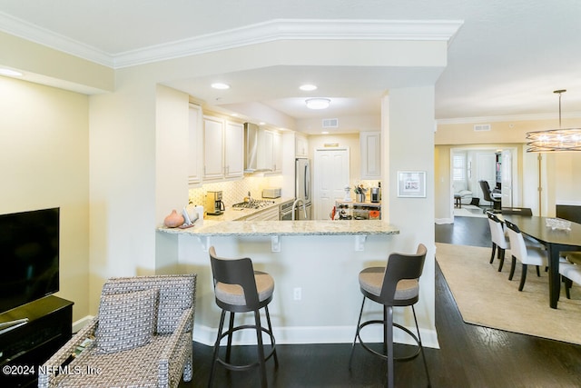 kitchen with appliances with stainless steel finishes, hanging light fixtures, white cabinets, dark wood-type flooring, and a breakfast bar