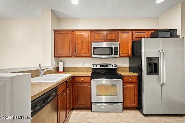 kitchen with sink, appliances with stainless steel finishes, a textured ceiling, and light tile patterned flooring