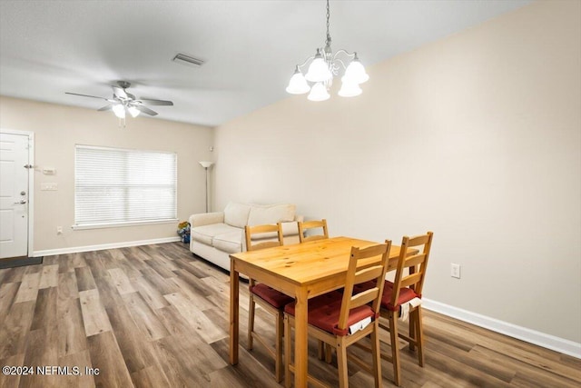 dining space with hardwood / wood-style flooring and ceiling fan with notable chandelier