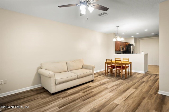 living room with ceiling fan with notable chandelier and hardwood / wood-style floors