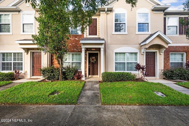 8121 Summer Palm Ct, Jacksonville, FL 32256 - townhome / multi-family property with brick siding, a front yard, and stucco siding