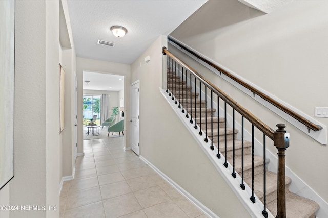 stairway with tile patterned flooring and a textured ceiling