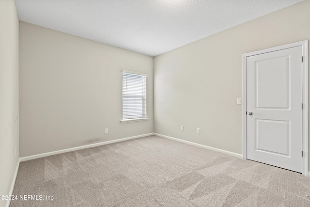 unfurnished room with a textured ceiling and light carpet