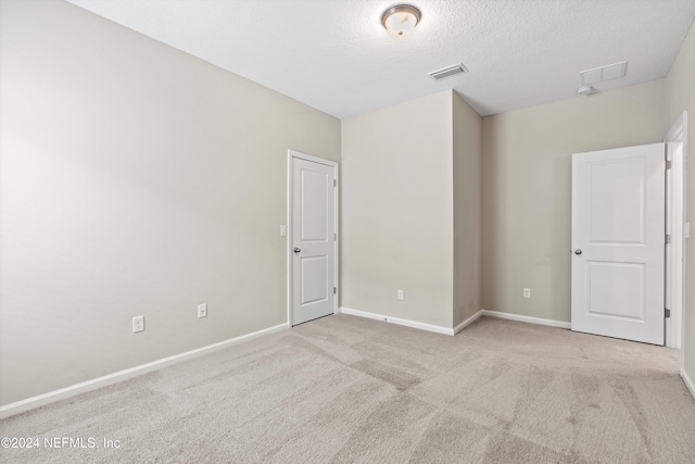 unfurnished room with light colored carpet and a textured ceiling