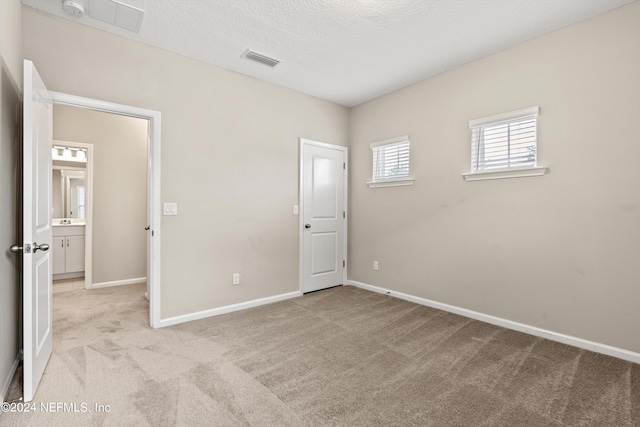 unfurnished bedroom with light colored carpet and a textured ceiling