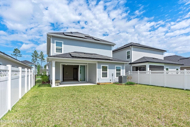 rear view of house with central AC unit, solar panels, a lawn, and a patio area