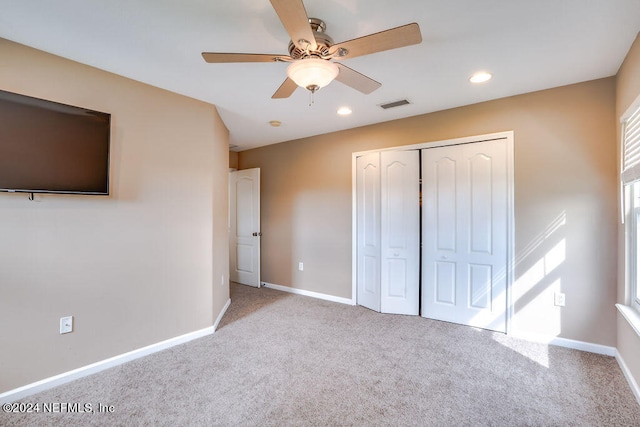 unfurnished bedroom featuring ceiling fan, a closet, and light carpet