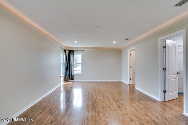 empty room with crown molding and light wood-type flooring