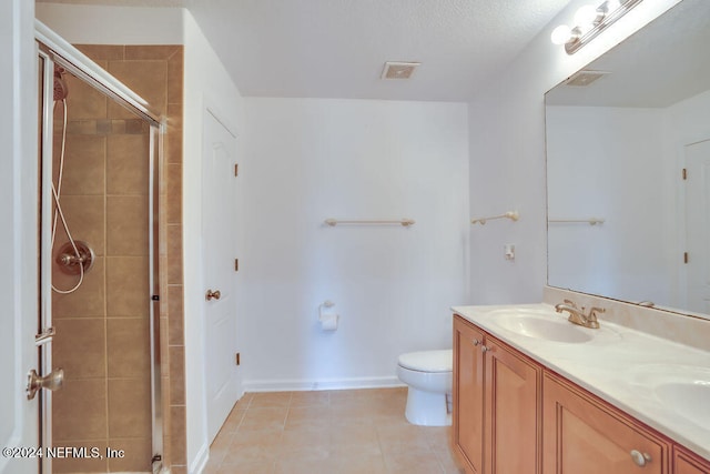 bathroom featuring tile patterned floors, vanity, toilet, and a shower with shower door