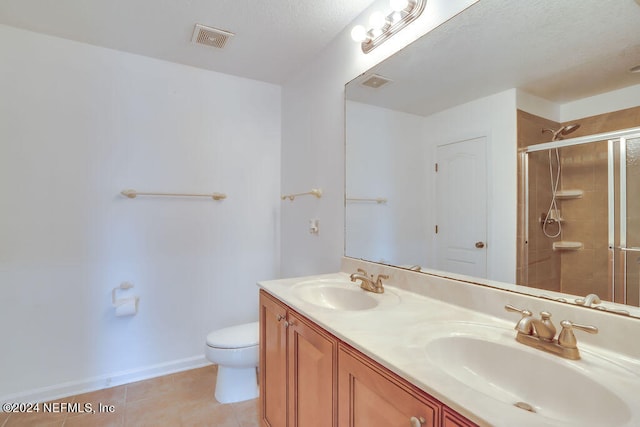 bathroom featuring tile patterned floors, toilet, vanity, and walk in shower