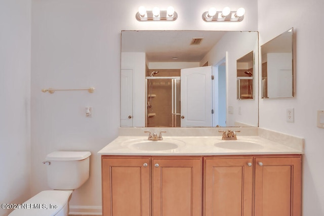 bathroom featuring vanity, toilet, and a shower with shower door