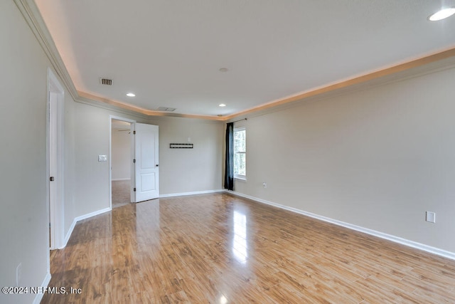 spare room featuring light wood-type flooring and crown molding