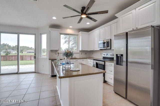 kitchen with light tile patterned flooring, a center island, white cabinets, and stainless steel appliances