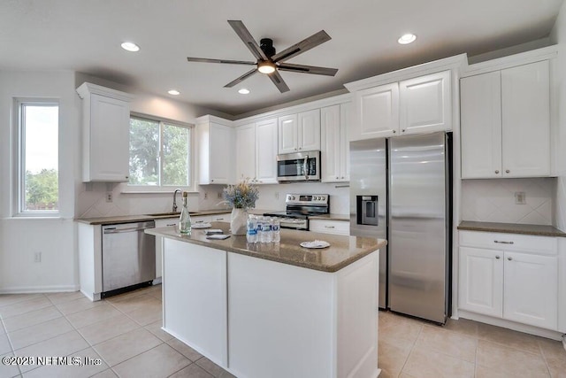 kitchen with a center island, dark stone counters, sink, white cabinetry, and stainless steel appliances