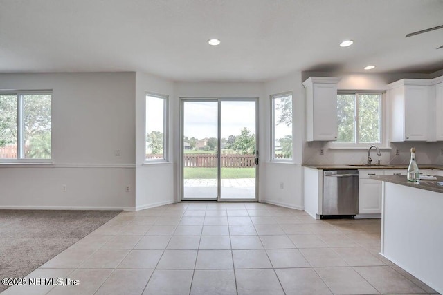 kitchen with white cabinetry, sink, light tile patterned floors, and stainless steel dishwasher