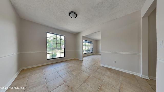 spare room featuring light tile patterned floors and a textured ceiling