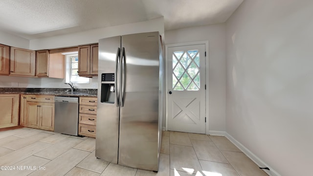 kitchen featuring appliances with stainless steel finishes, a healthy amount of sunlight, dark stone counters, and a textured ceiling