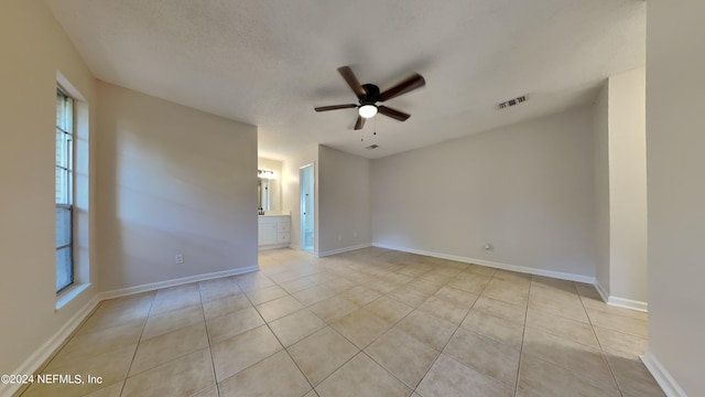 unfurnished room with ceiling fan, a textured ceiling, and light tile patterned floors