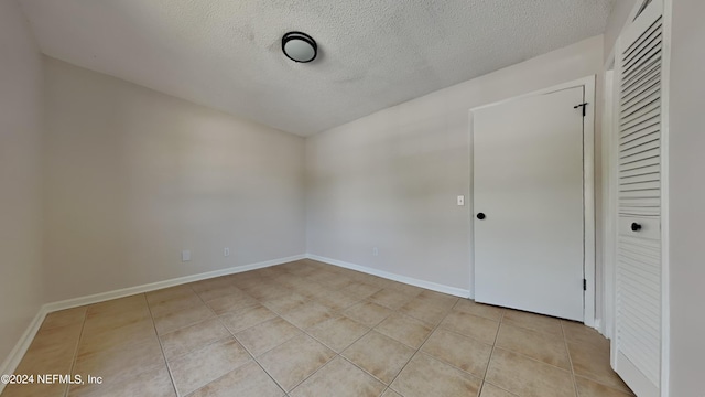 spare room with light tile patterned flooring and a textured ceiling