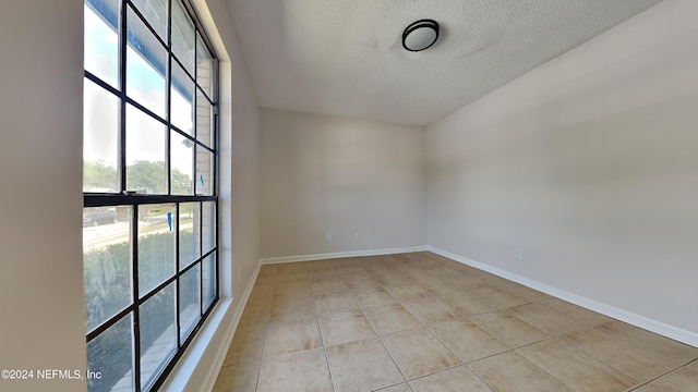 empty room with a textured ceiling and light tile patterned floors