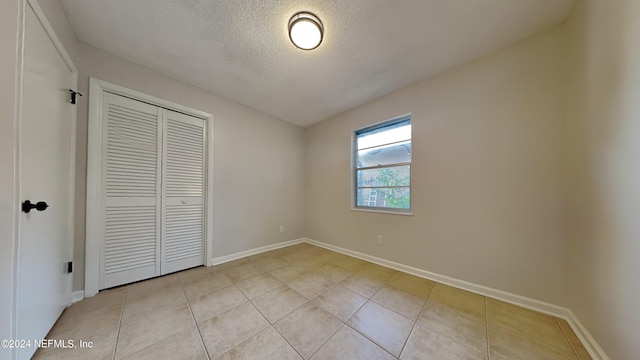 unfurnished bedroom with a textured ceiling, a closet, and light tile patterned flooring