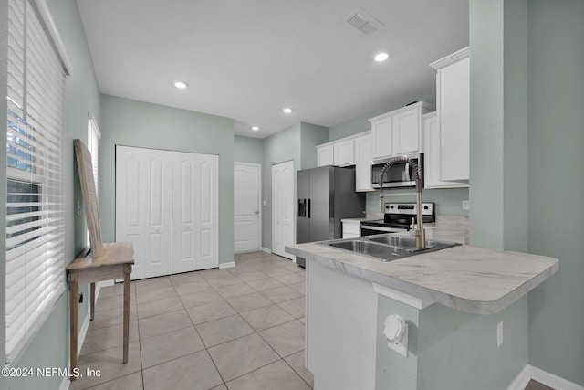 kitchen featuring a breakfast bar, white cabinets, kitchen peninsula, appliances with stainless steel finishes, and light tile patterned floors