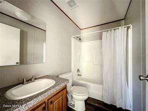 full bathroom with vanity, shower / bath combo with shower curtain, and toilet