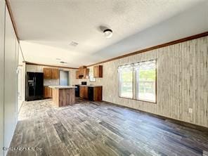 kitchen with wood walls, hardwood / wood-style floors, black refrigerator, and a kitchen island