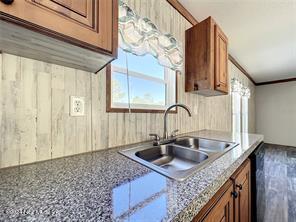 kitchen with crown molding, sink, and light stone countertops