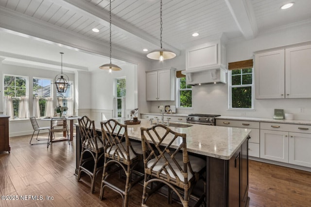 kitchen featuring beam ceiling, decorative light fixtures, dark wood finished floors, high end stainless steel range oven, and a sink