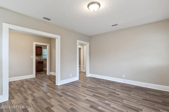 unfurnished bedroom featuring crown molding, hardwood / wood-style floors, and a textured ceiling