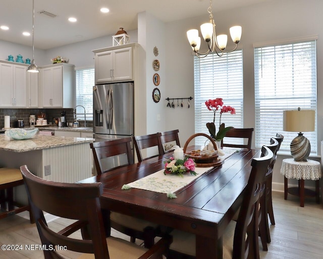 dining room with an inviting chandelier, sink, and light hardwood / wood-style floors