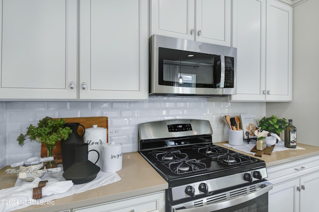 kitchen with white cabinets, appliances with stainless steel finishes, and backsplash