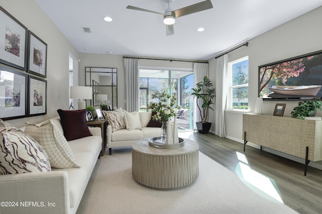 living room featuring wood-type flooring, ceiling fan, and a wealth of natural light