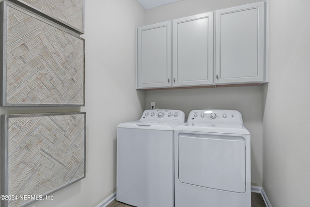 clothes washing area with washer and dryer and cabinets