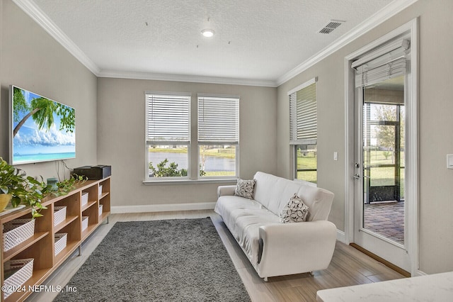 living area featuring light hardwood / wood-style floors, a textured ceiling, and crown molding