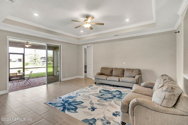 living room with ceiling fan, a raised ceiling, and ornamental molding