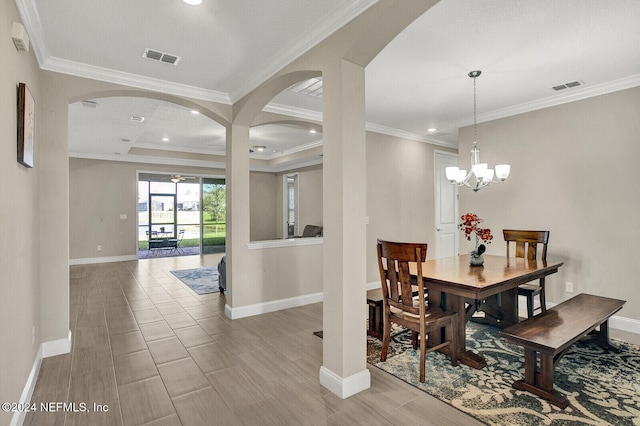 dining space featuring a chandelier, a raised ceiling, light hardwood / wood-style floors, and crown molding