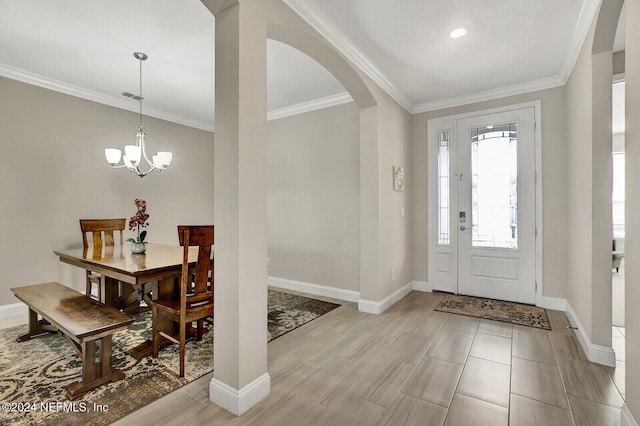 entryway featuring a chandelier, light wood-type flooring, and ornamental molding