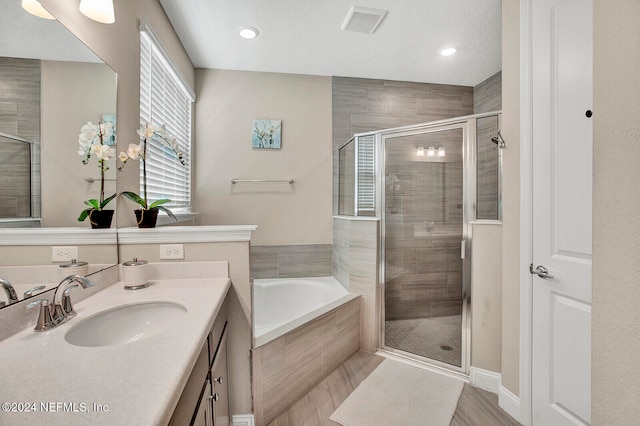 bathroom featuring vanity, shower with separate bathtub, and a textured ceiling