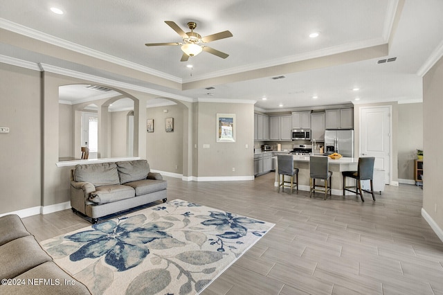 living room with ceiling fan, light wood-type flooring, and ornamental molding