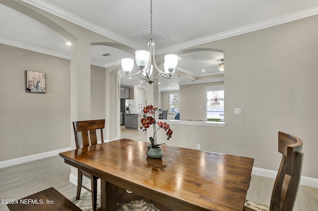 dining area with ceiling fan with notable chandelier, light hardwood / wood-style floors, and crown molding