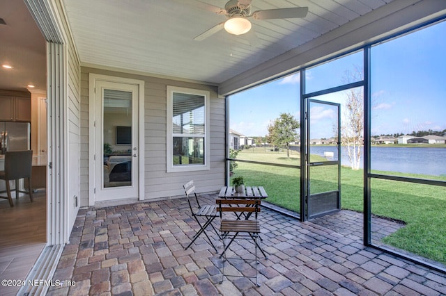 sunroom featuring ceiling fan and a water view