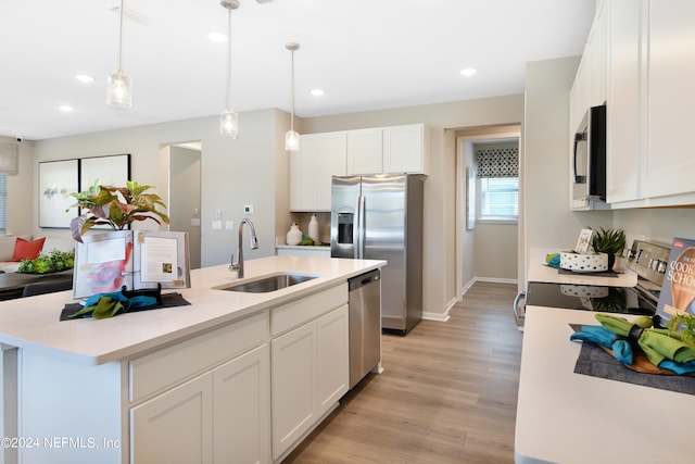 kitchen featuring an island with sink, white cabinets, sink, light hardwood / wood-style flooring, and appliances with stainless steel finishes